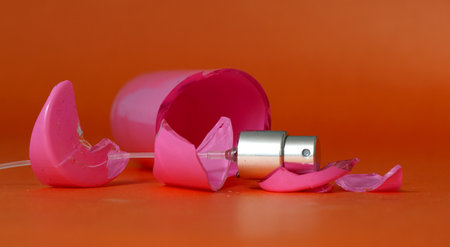 Broken pink perfume bottle on orange background.の写真素材