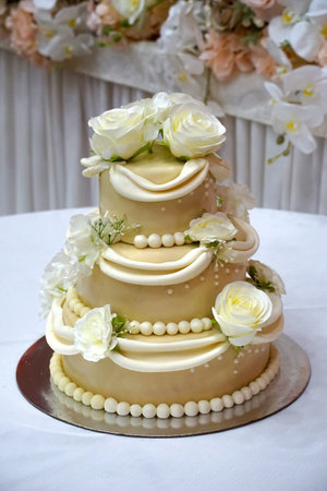 Three-tiered white wedding cake decorated with flowers on a table.の写真素材