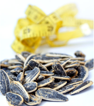 salty sunflower seeds wuth yellow tape measure on the back . diet conceptの写真素材