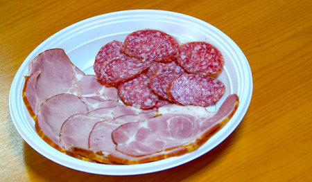 Smoked salami ,pepperoni and ham slices, in a plastic disposable plateの写真素材