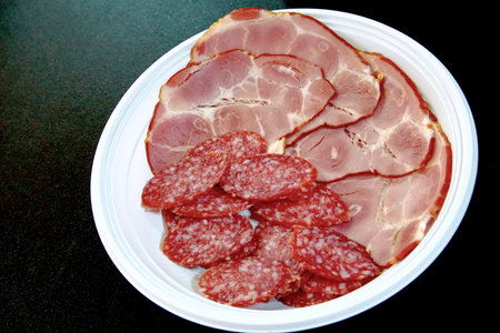Smoked salami ,pepperoni and ham slices, in a plastic disposable plateの写真素材