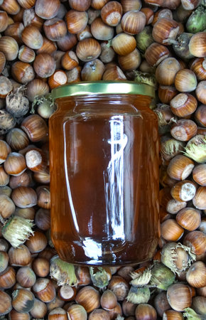 Honey in glass jar and fresh harvested organic hazelnuts,Natural organic products conceptの写真素材