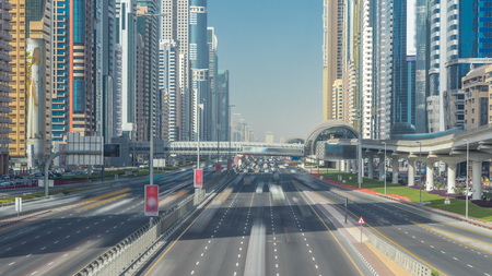Busy Sheikh Zayed Road traffic timelapse, metro railway and modern skyscrapers around in luxury Dubai city, United Arab Emirates. Sunny clear day with blue sky. View from bridgeのeditorial素材