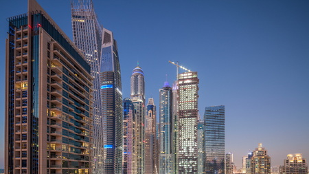 Aerial view of modern skyscrapers day to night transition timelapse before sunrise in Dubai Marina with yachts in Dubai, UAE. Illuminated towers at eveningのeditorial素材