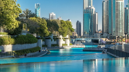 Evening view of cascade of water near dancing fountains in downtown timelapse during sunset in Dubai, UAE. Modern skyscrapers on background reflected in waterのeditorial素材