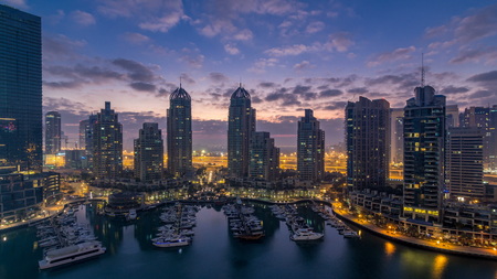 Aerial view of modern skyscrapers night to day transition timelapse before sunrise in Dubai Marina with yachts in Dubai, UAE. Illuminated towers early morningのeditorial素材