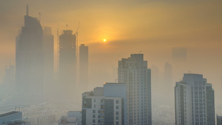 Foggy morning sunrise in downtown of Dubai timelapse. Futuristic view of the city skyscrapers covered in mist. Aerial view from rooftop with modern towers. Dubai, UAEの写真素材