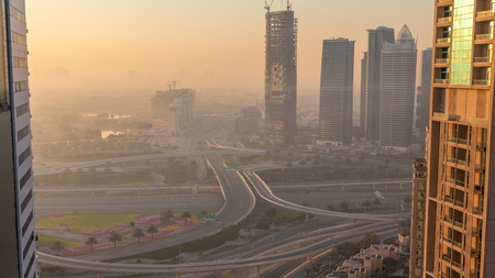 Aerial view of a road intersection in a big city at sunrise timelapse. Urban landscape of Dubai Marina district in UAE with cars and skyscrapers.の写真素材