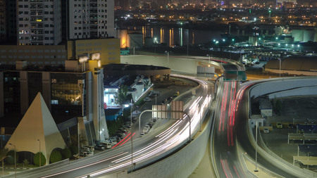 Cityscape of Ajman with traffic on main road overpass from rooftop at night with lights timelapse....