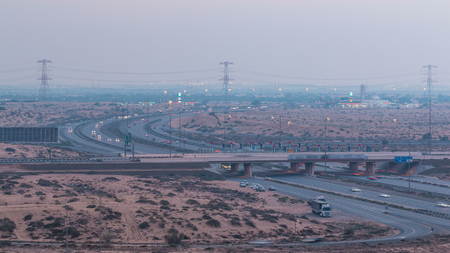 Highway roads in desert with traffic day to night timelapse in a big city from Ajman to Dubai before...