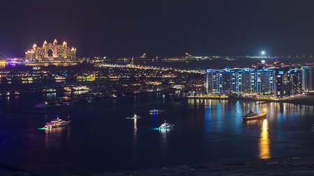 Palm Jumeirah with yahcts with hotel at night view from skyscraper Dubai marina timelapse,Palm Jumeirah is a hugely popular residential area located in the sea.の写真素材