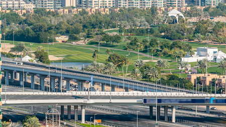 Golf field timelapse from top at day time with traffic on sheikh zayed road. Green grass of the golf...