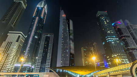 Downtown Dubai towers night timelapse hyperlapse. View of Sheikh Zayed road with tall skyscrapers. Traffic on the road and metro line. Blinking lights and trailsの写真素材