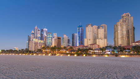 View of modern skyscrapers day to night transition timelapse in Jumeirah beach residence in Dubai,...