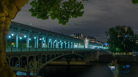 View of pont de Bir-Hakeim (formerly pont de Passy) night timelapse - a bridge that crosses the Seine River. Central arch decorated with monumental statues. Cars and trains traffic on road. Paris, Franceの写真素材
