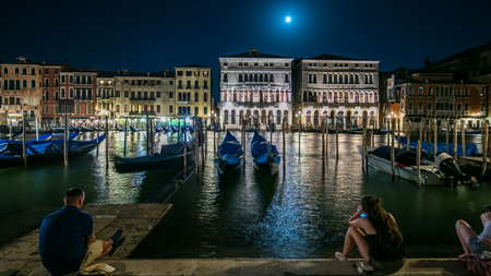 The magnificent Palazzo Balbi overlooking the Grand Canal in Venice night timelapse. People sitting and gondolas on foreground. Now home to the President and local government of the Veneto region of Italy.の写真素材