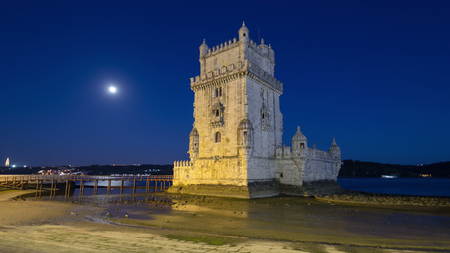 Lisbon, Portugal. Belem Tower (Torre de Belem) is a fortified tower located at the mouth of the Tagus River timelapse hyperlapse with full Moon, lights turning on 4Kのeditorial素材