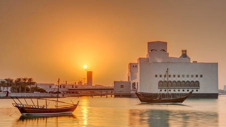 DOHA, QATAR - CIRCA JAN 2018: Sunset near Museum of Islamic Art in Doha timelapse, Qatar, view with the emerging high-rise skyline behind it. Old boats on foreground.のeditorial素材