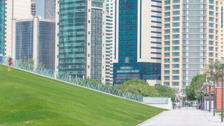 The high-rise district of Doha timelapse, seen from the Hotel Park, with green lawn and artificial...