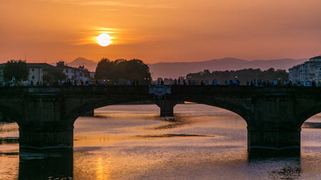 Cityscape view on Arno river with famous Holy Trinity bridge timelapse on the sunset in Florence. Reflections on water. Orange skyの写真素材