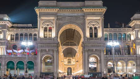 Night view of illuminated Vittorio Emanuele II Gallery timelapse in Milan, Italy. People walking on Square Piazza Duomo near entrance.のeditorial素材