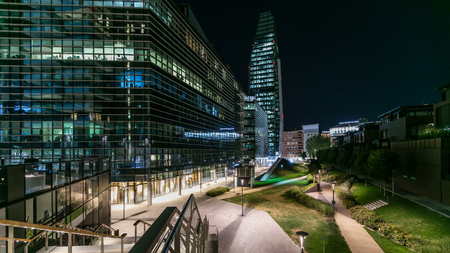 Milan Porta Nuova business district at night transition timelapse. Green lawn in park and Lights in windows of skyscrapersの写真素材