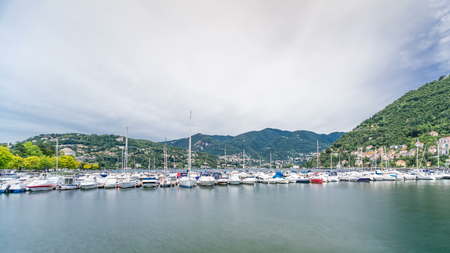 Landscape with Lake Como timelapse, Lombardy, Italy. Houses and boats on background. Cloudy sky at summer day.の写真素材