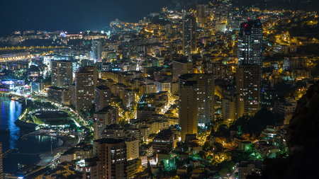 Aerial top view of Monaco from the grand corniche road night timelapse, Monaco France. Evening illumination. Traffic on the road. Reflections in water of harborの写真素材