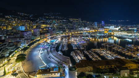 Panorama of Monte Carlo timelapse hyperlapse at night from the observation deck in the village of Monaco with Port Hercules. Buildings with illumination and yachts in harbor aerial top view. Traffic on the roadの写真素材