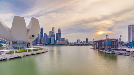 Futuristic architecture flower shape design of the Art Science museum at the foreground timelapse at sunset and at the background the skyscrapers skyline city of Singapore.のeditorial素材