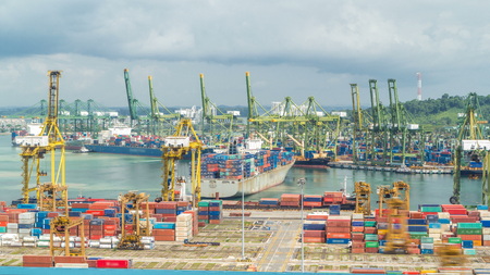 Commercial port of Singapore timelapse. Bird eye panoramic aerial view of busiest Asian cargo port with hundreds of ships loading export and import goods and thousands of containers in harborの写真素材