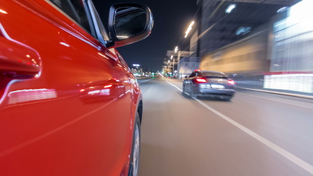 Driving from side of fast car moving on a night avenue in city  , road with lights reflected on car on high speed. Rapid rhythm of a modern city.の写真素材