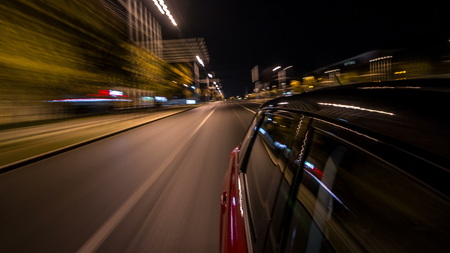 Driving from side of fast car moving on a night avenue in a city  , road with lights reflected on car at high speed. Rapid rhythm of a modern city.の写真素材