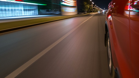Driving from side of fast car moving on a night avenue in a city  , road with lights reflected on...
