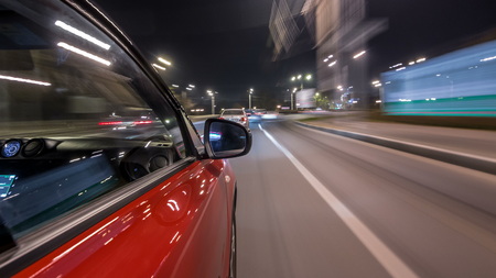 Driving urban look from fast driving car at a night avenue in a city  , road with lights reflected on car at high speed. Rapid rhythm of a modern city.の写真素材