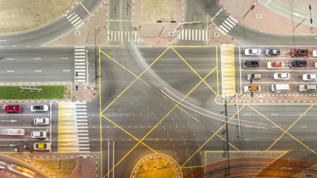 Aerial top view of a road intersection in a big city night timelapse. Urban landscape of Dubai Marina district in UAE with cars and tram line.の写真素材