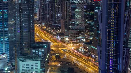 Aerial view of towers in Business Bay with traffic on the road night timelapse. Big modern city with...