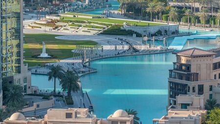 Top close up view of the bridge over man-made lake and some people walking in park with hand monument evening timelapse in Dubai downtown, United Arab Emirates.の写真素材