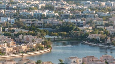 Aerial view to villas and houses with Golf course with green lawn and lakes timelapse. Traffic on streets. Warm evening lightの写真素材
