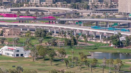 Crossroad near Dubai Marina and golf course morning timelapse, Dubai, United Arab Emirates. Aerial view from Greens district. Green lawn and traffic on a highwayの写真素材
