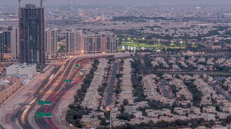 Jumeirah Lake Towers residential district aerial day to night transition timelapse near Dubai Marina. Illuminated modern skyscrapers and traffic on the road from aboveの写真素材