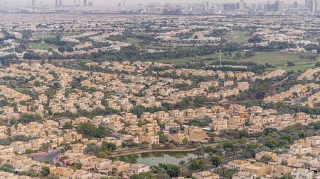 Aerial view of apartment houses and villas with golf course in Dubai city timelapse near jumeirah lake towers district, United Arab Emirates. Top fiew from skyscraperの写真素材