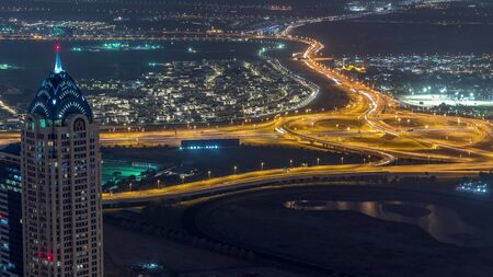 Panoramic aerial view of business bay towers in Dubai night timelapse. Rooftop view of some illuminated skyscrapers, traffin on crossroad and new towers under construction.の写真素材