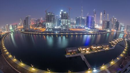 Panorama of the modern city during all night timelapse with lights switching off. Aerial view of graceful canal and luxury skyscrapers in Business Bay, Dubai, United Arab Emiratesの写真素材