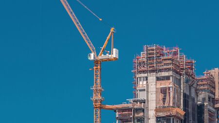 Aerial view of a skyscrapers under construction with huge cranes timelapse in Dubai. Business bay district with blue sky on a background. United Arab Emiratesの写真素材