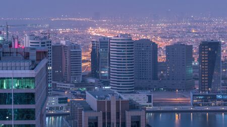 From night to day transition aerial timelapse before sunrise in big city with futristic buildings and illuminated roads in Business Bay, Dubai, United Arab Emiratesの写真素材