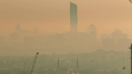 Aerial view to Dubai Creek with festival city during sunrise timelapse. Orange morning fog and construction site from Downtown. Dubai - UAEの写真素材