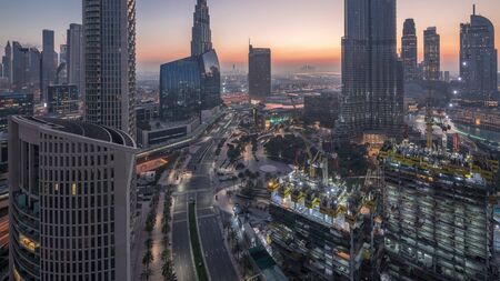Panoramic skyline view of Dubai downtown before sunrise with mall, fountains and traffic on a road aerial night to day transition timelapse. Modern skyscrapers and construction siteの写真素材