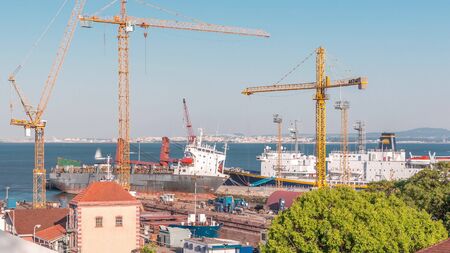 Skyline over Lisbon commercial port timelapse, containers on pier with freight cranes, ship...