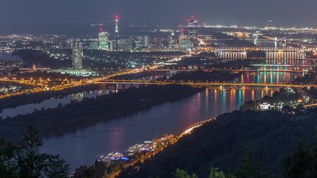 Skyline of Vienna from Danube Viewpoint Leopoldsberg aerial night timelapse. Bridges over the river,...
